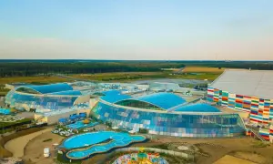 Nowoczesny kompleks z basenami i zjeżdżalniami, największy park wodny w Polsce, otoczony zielenią.