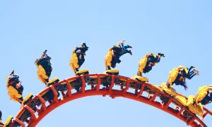 Mayan Energylandia: pędząca kolejka z pasażerami w żółtych wagonikach, doświadczającymi ekstremalnej prędkości i przeciążeń.