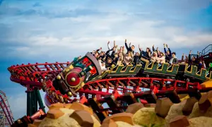 Energylandia pociąg z pasażerami wznosi się na torach kolejki górskiej, wszyscy krzyczą z radości.
