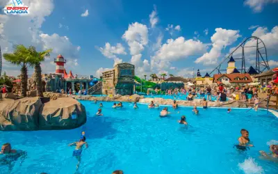 Energylandia wodne atrakcje: ludzie kąpią się w basenie, zjeżdżalnie i roller coaster w tle.