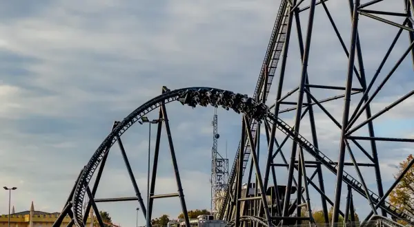 Pasażerowie na wagonikach pędzą po torach najszybszego rollercoastera w Europie, który wznosi się ku niebu.