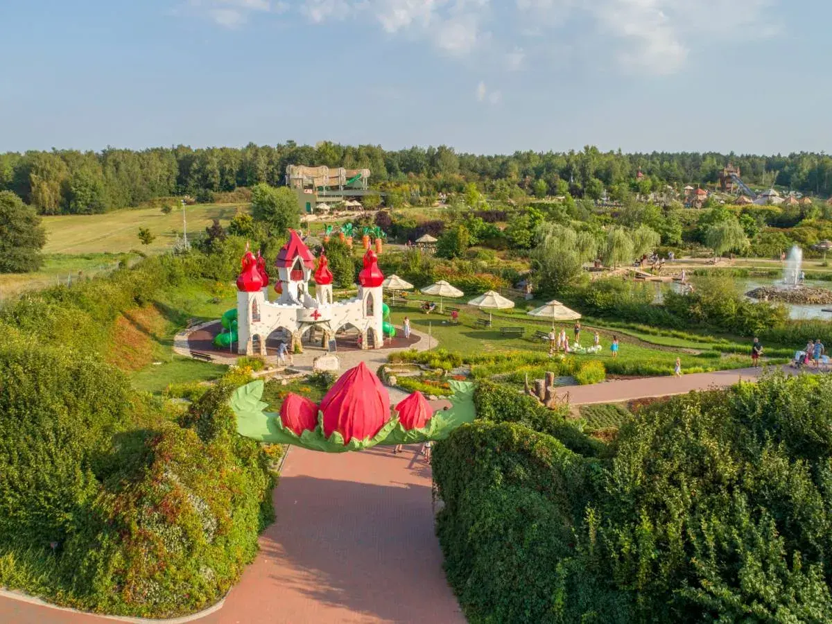 Bajkowy zamek i plac zabaw, gdzie są magiczne ogrody. Dzieci bawią się wśród zieleni i kolorowych kwiatów.