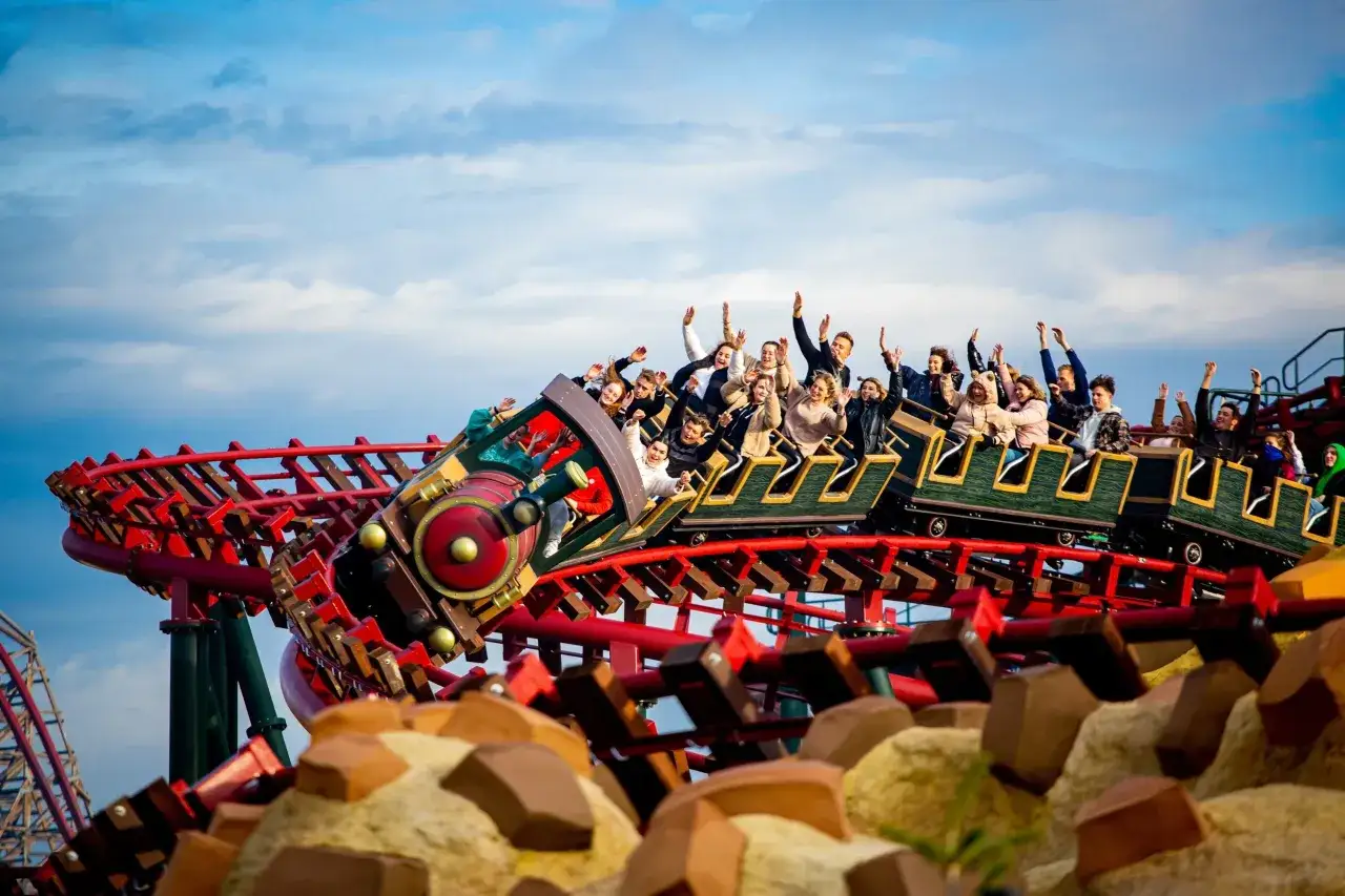 Energylandia pociąg z pasażerami wjeżdża na szczyt, unosząc ręce w geście radości.
