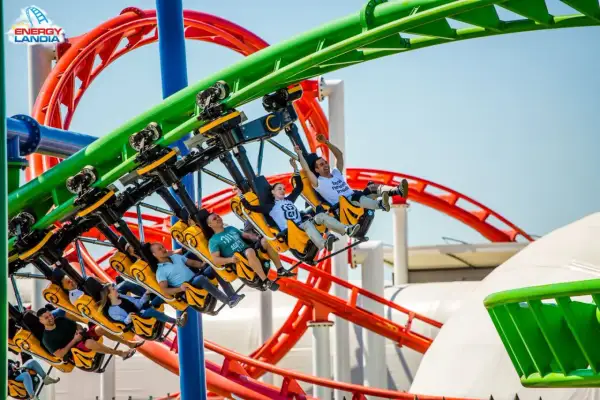 Ludzie krzyczą z radości na żółtych wagonikach rmf dragon roller coaster w Energylandii.