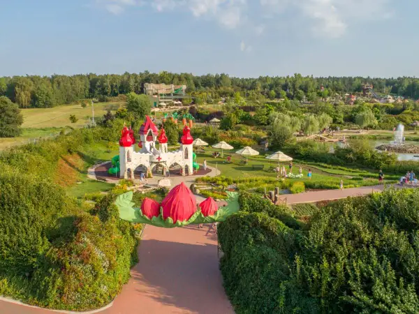 Bajkowy zamek i plac zabaw, gdzie są magiczne ogrody. Dzieci bawią się wśród zieleni i kolorowych kwiatów.